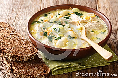 Hearty cream soup with gnocchi, chicken and spinach served with bread close-up in a bowl. horizontal Stock Photo