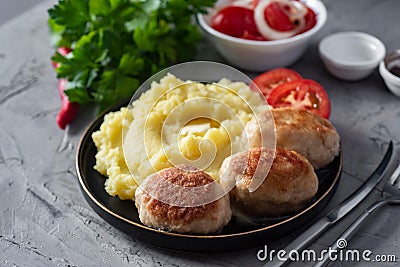 A hearty lunch for the family: mashed potatoes and a meat patty on a plate on a wooden table. Close-up Stock Photo