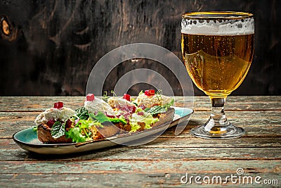 Hearty snack with different kinds of spreads on farmhouse bread served with a fresh yeast wheat beer on an old wooden table. Stock Photo