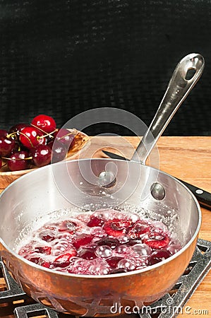 Heated cherries jubilee in copper pan Stock Photo