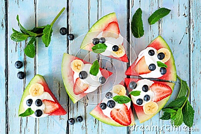 Heathy watermelon pizza witHealthy watermelon pizza with blueberries, strawberries, bananas and yogurt, top view over blue wood Stock Photo