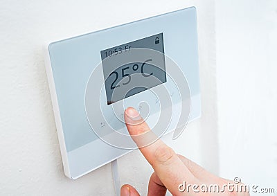 Heating concept. Hand is adjusting temperature in room on digital thermostat control. Stock Photo