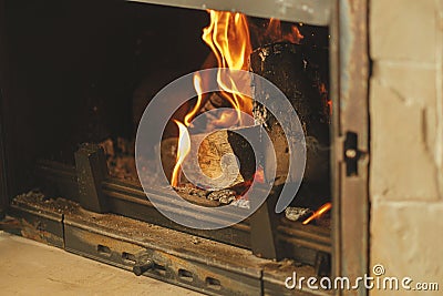 Heating house in winter with wood burning stove. Burning firewood in fireplace in rustic room. Fireplace heating alternative to Stock Photo