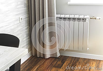 Heating metal radiator, white radiator in modern apartment interior with wooden floor Stock Photo