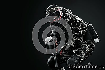 Heavily armed masked paintball soldier isolated on black background. Ad concept. Stock Photo