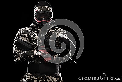 Heavily armed masked paintball soldier isolated on black background. Ad concept. Stock Photo