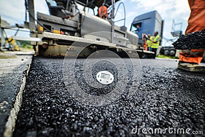 Heavy duty road building. Hot Asphalt being laid and measured for a quality check as a part of a on site control test. Stock Photo