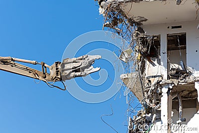 Heavy equipment hydraulic shears arrow dismantle the building, demolition destruction Stock Photo