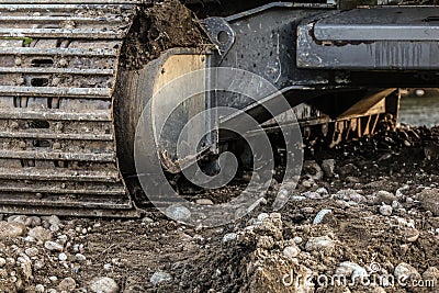 Heavy excavator digger machine track detail, some stones in foreground. Abstract industrial / construction background Stock Photo