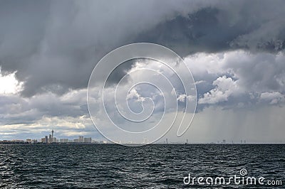 Heavy gray rain clouds happen in the city near sea Stock Photo