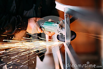 Heavy industry worker cutting steel with angle grinder on construction site Stock Photo