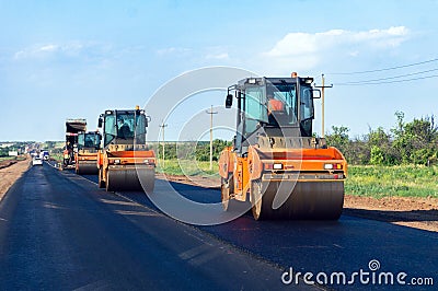 Heavy orange road rollers compacts the bitumen layer of newly laid asphalt. Reconstruction of a roadway Stock Photo