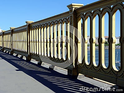 Heavy and rugged cast iron yellow color bridge railing with strong shadow Stock Photo