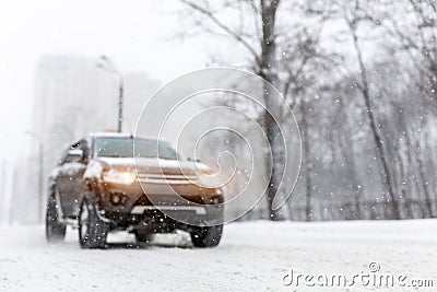 Heavy snowfall and blurred SUV awd car on road. 4wd vehicle on city street at winter. Seasonal roadside assistance concept. Stock Photo