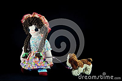 Heel Puppy, let`s go for a walk. Vintage girl rag doll with her puppy; presented on a plain black background. Stock Photo