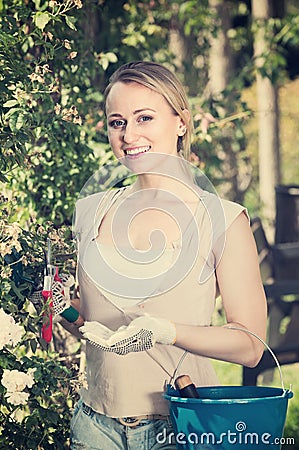 Ñheerful young woman holding horticultural tools in garden Stock Photo