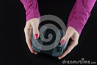 Top view of woman hands with pink nail polish on fingers holding a Nintendo Switch gaming controller for video games Editorial Stock Photo