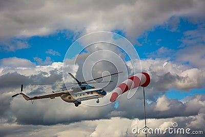 Helicopter flying in cloudy sky and windcone Stock Photo