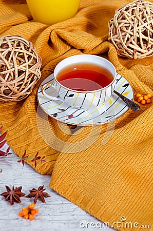 Hello Autumn background. Bright yellow wool sweater, cup of tea, honey, vine balls, anise stars, sea buckthorn berries Stock Photo