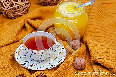 Hello Autumn background. Bright yellow wool sweater, cup of tea, honey, vine balls, anise stars and walnuts Stock Photo
