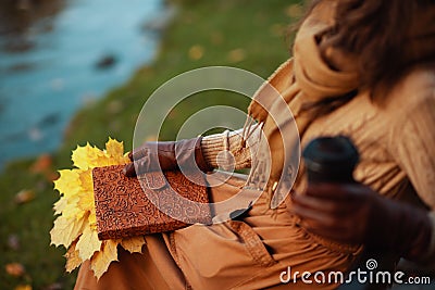Closeup on woman with notebook, yellow leaves drinking coffee Stock Photo