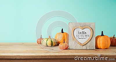 Hello Autumn concept with photo frame and pumpkin decor on wooden table over blue background. Fall season greeting card Stock Photo