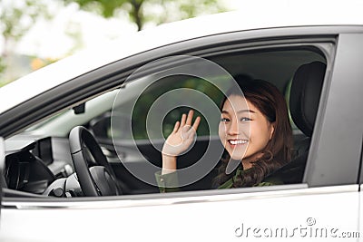 Hello! Beautiful young cheerful woman looking at camera with smile and waving while sitting in her car Stock Photo