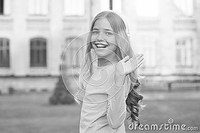 Hello gorgeous. Happy child wave hand outdoors. Little child smile in casual style. Small child wear long wavy hair Stock Photo