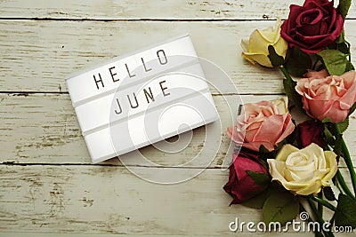 Hello June Word on Light box with roses flower bouquet on wooden background Stock Photo