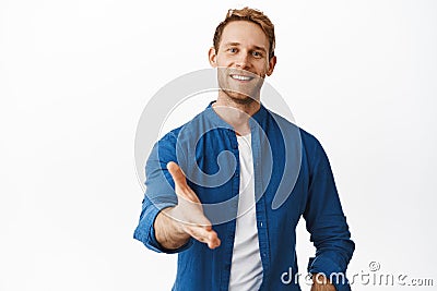 Hello nice to meet you. Smiling handsome redhead man extend hand for handshake, look friendly, greet you, hi gesture Stock Photo