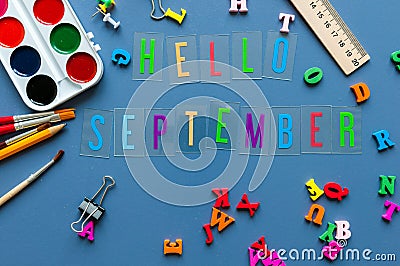 Hello September text on teacher or pupil table with school supplies side border on a blue background Stock Photo