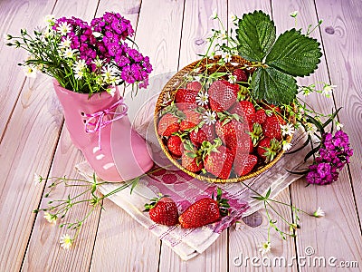 Hello summer concept. Ripe strawberries in a basket, a bouquet of wild flowers in a pink shoe Stock Photo