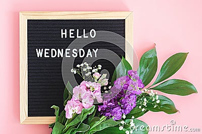 Hello Wednesday text on black letter board and bouquet colorful flowers on pink background. Concept Happy Wednesday. Template for Stock Photo