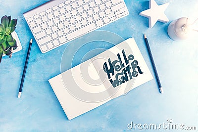 Hello winter graphic handlettering in Open notebook with keyboard on blue table top view flat lay mock up Stock Photo