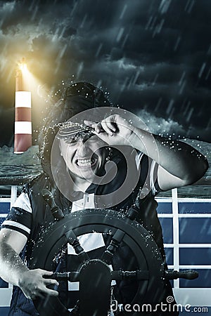 Helmsman with vest and cap struggle against storm in front of th Stock Photo