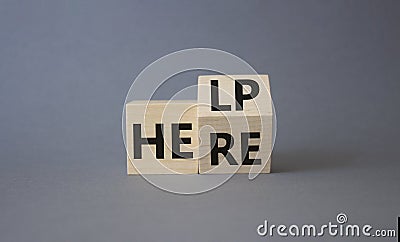 Help is here symbol. Turned wooden cube with words Here to Help. Beautiful grey background. Business and Help is here concept. Stock Photo