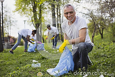 Happy senior volunteer gathering trash Stock Photo