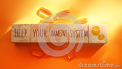 Help your immune system words made with wooden building blocks and Omega-3 pills on orange background. Healthcare concept Stock Photo