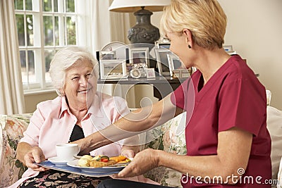 Helper Serving Senior Woman With Meal In Care Home Stock Photo