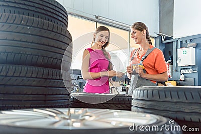 Helpful female auto mechanic checking the identification number of a tire Stock Photo