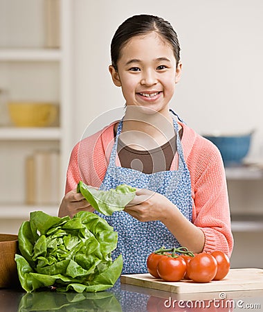 Helpful girl preparing salad in kitchen Stock Photo