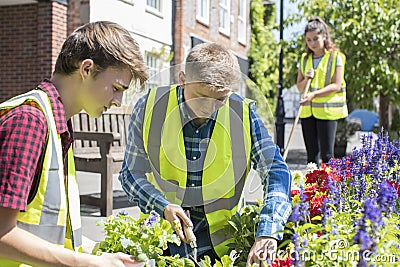 Group Of Helpful Teenagers Planting And Tidying Communal Flower Stock Photo