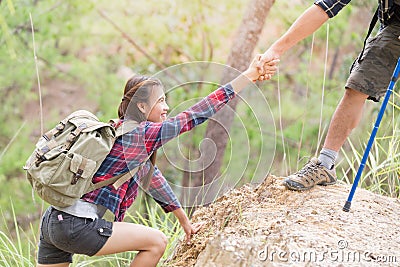 Helping hand - hiker woman getting help on hike smiling happy overcoming obstacle. Tourist walking on the Mountain, Young couple Stock Photo