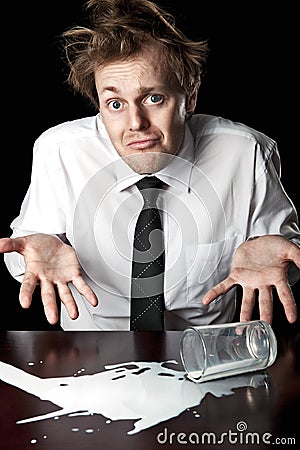 Helpless businessman with spilled milk on table Stock Photo