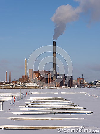 A wintery scene of an urban powerplant with frozen lake in the foreground Stock Photo