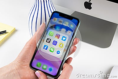 Apple iPhone 11 in woman hands with icons of social media facebook, instagram, twitter, snapchat application on screen. Social med Editorial Stock Photo