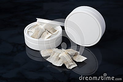 Closeup of a white swedish snus can and portion snuff pouches Stock Photo