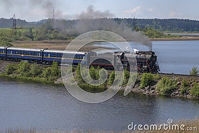 Steam locomotive L-0522 with tourist retro train `Ruskeala Express` on the dam Editorial Stock Photo