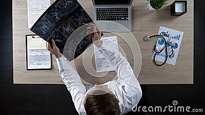 Hematologist holding scan of blood vessels, thinking about diagnosis, top view Stock Photo