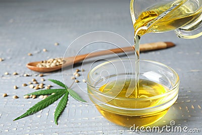 Hemp oil pouring from sauce boat into bowl Stock Photo